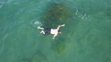 Denizde yüzen, açık denizde yüzen bir adam.