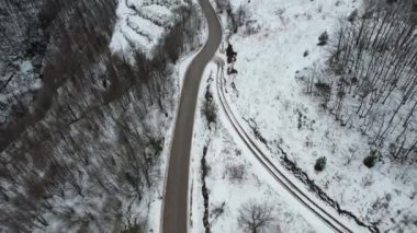 Kışın karlı orman ve kırsal yol havadan çekilmiş.