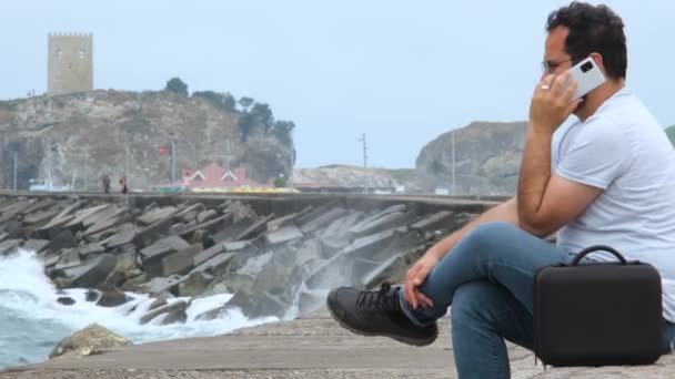 男人坐在海岸上 体贴的男人坐在海岸上 讲电话 — 图库视频影像