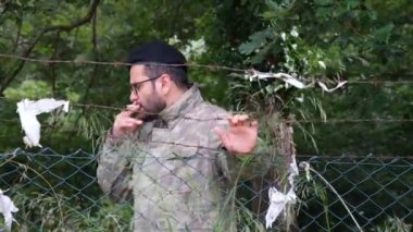 Siyah bereli paralı asker çitlerin arkasında sigara içiyor, paramiliter