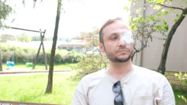 Gözü bandajlı adam güneş gözlüğü takıyor.