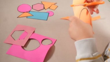 Çocuk renkli karton keserek bir aktivite yapıyor