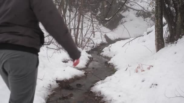 雪の中のクリークを歩いている男 — ストック動画