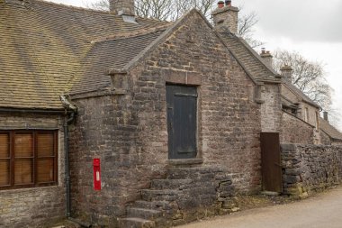 Duvarında kırmızı bir İngiliz posta kutusu olan eski bir Peak District taş binası.