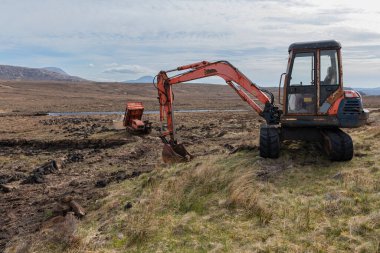 Mekanik kazıcı kullanarak İskoçya 'da bir vadide turba kazmak ve Barrow' u izlemek.