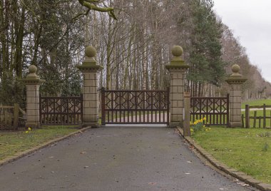 Büyük kahverengi ahşap kapılar kumtaşı direkleri ve yuvarlak top toplarıyla kaplıdır.