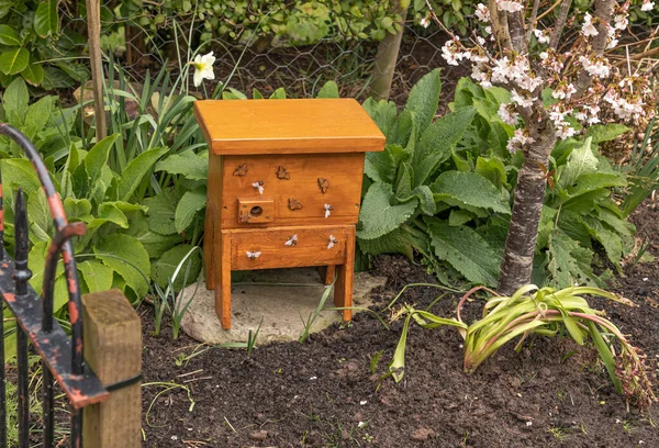 Bumble bee box in the border of a garden made of wood with fake Bumblebees attached