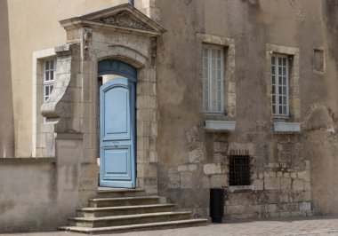 Eski krem renkli taş kapı, birkaç basamak yukarıda.