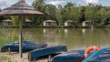 Gölün karşısındaki manzarayı. Uzak kıyıda kulübeleri ve ön planda kanoları olan.