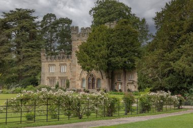 Demirden bir çitin arkasındaki ağaçlarda bir kale.