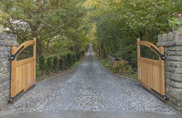 Open gates looking down a driveway that is lined by trees