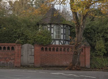 Hexygon, çatıda yeşil yosun olan kırmızı tuğla bir duvarın arkasında siyah beyaz bir bina sıçtı.