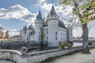 Corner view of an acient castle across a moat in the cool winter sunshine clipart