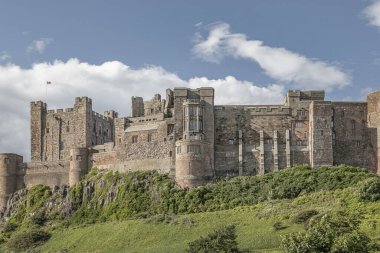 Kuzey Yorkshire, Bamburgh - 26 Haziran 2023 - Bayrağı dalgalanan bir tepedeki bir kalede çim yamacına bakıyorum