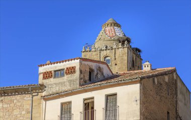 Leylek yuvalarıyla boyanmış ve etrafı binalarla çevrili eski bir bina.