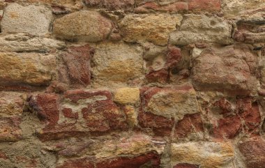 Birçok renkten oluşan aşınmış kumtaşı duvar. İnekleyin, sarı, altın, kırmızı.