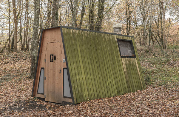 Экологически чистый компостный туалет в лесах, окруженный опавшими листьями