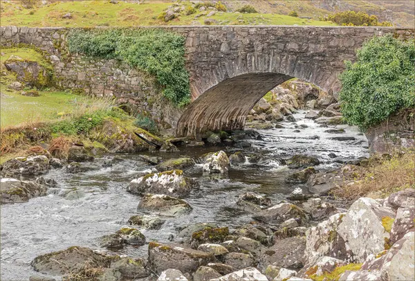 Sığ bir dere ilkbaharın başlarında eski bir taş köprünün altından hızla akıyor.