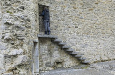 Eski bir taşın tepesindeki bir erkek bir kalenin kenarına bağlanmış bir kapı aralığına bakıyor.