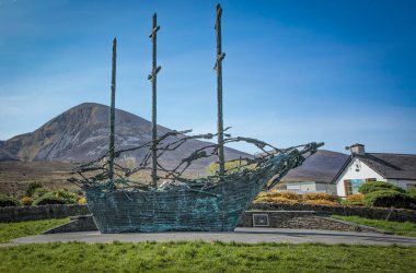 Murrisk, Demesne, Murrisk, County Mayo, Ireland - April 20th 2024 - Irish monument to the famine depicting close ups  of skeletons on a sailing ship set against the Craiogh Patrick mountain clipart