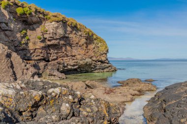 Temiz turkuaz suyu ve güzel mavi gökyüzü olan küçük kayalık bir koy.