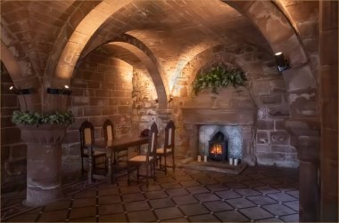 Yemek masası ve yanında sandalyeler olan, kubbeli tavanlı eski bir şömine.