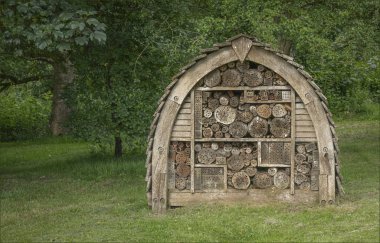 İhtişamlı bir evin bahçesinde, bazı ağaçların yakınında büyük kemerli bir böcek evi.