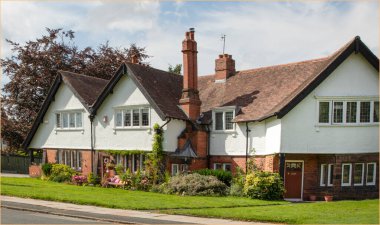 Port Sunlight, Wirral, İngiltere - 26 Temmuz 2024 - Bahçesinde uzun bir bacası ve bankı olan ev