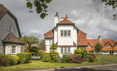 Port Sunlight, Wirral, İngiltere - 26 Temmuz 2024 - Süslü bahçesi ve çizgili bankı olan eski bir evin kapısına bakıyor