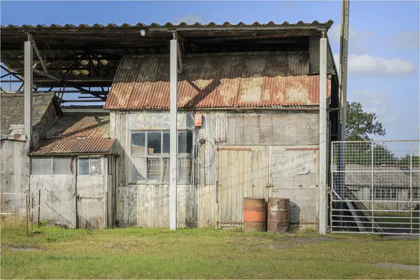 stock image Beeston, Cheshire West and Chester, UK - August 14th 2024 -Old corrugated iron sheds built under the roof of a barn