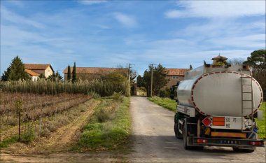 Fitou, Languedoc, Fransa - 18 Kasım 2024 - Tanker sonbahar sarmaşıklarını geçerek küçük bir yola giriyor 