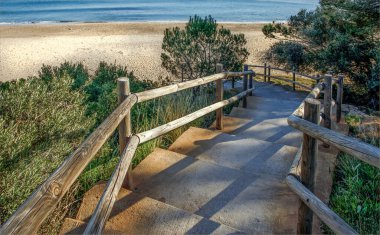 Costa Dourada, İspanya - 15 Aralık 2024 - uzak bir sahile doğru uzanan el rayları olan merdivenler