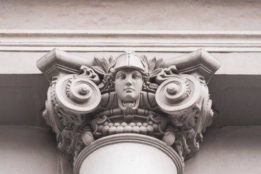 Üstünde kadın heykeli olan bir sütun. Heykel bir kask takıyor. Sütun beyazdır.