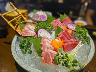 Etli ve sebzeli bir tepsi suşi. Suşi kapaklı bir kasede servis edilir.