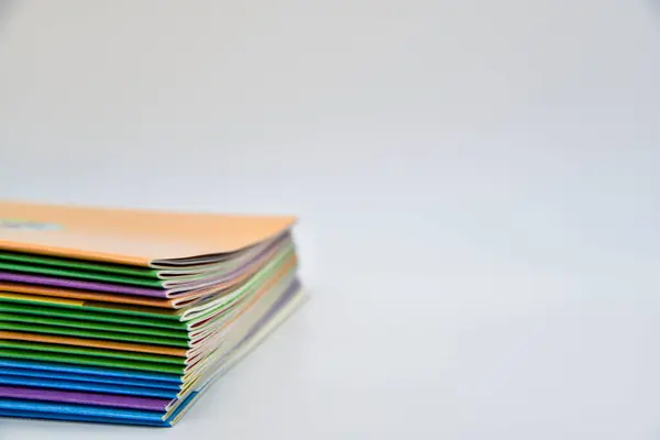 Farklı renkli kapaklı bir yığın kitap. Kitaplar üst üste istiflenmiş. En üstteki kitap turuncu.
