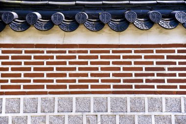 Kırmızı tuğlalı bir duvar. Duvar tuğladan yapılmış ve beyaz bir sınırı var.