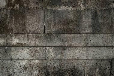 Gri renkli taştan yapılmış bir duvar. Duvar eski ve bir sürü çatlağı var.