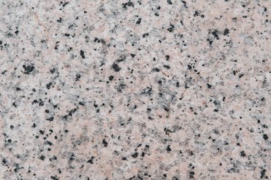 Bir sürü küçük deliği olan taş bir duvar. Delikler siyah ve beyaz. Duvar gri.