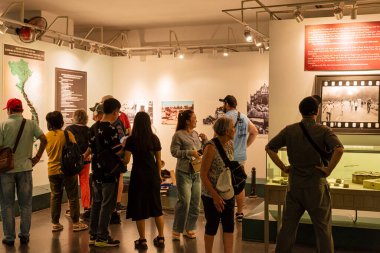 Bir grup insan bir müzede duruyor. Grupta bir erkek ve bir kadın da dahil olmak üzere birkaç kişi var.