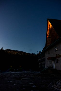 Dağlarda sabah, binanın yanındaki oyun parkı, ladin ağaçları, köknar ağaçları, orman, pansiyon, dinlenme merkezi, yol, gölgeler, kar, güneş, doğa, manzara, seyahat, ağaçlar, kar, kış