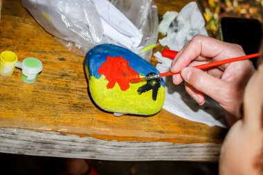 Kız, bir kemikle bir taş boyuyor ve resim, yüz, çocuk çizimleri, renkli, oyuncak.