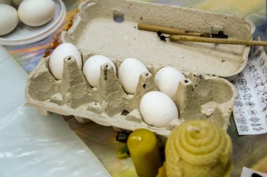 Beyaz tavuk yumurtaları, karton bir kutuda, 10 parça, sarı mumlar, resim yapmak için alet, kalem, çizimler, masanın üstünde, Paskalya, el işi, bayram, çocukluk, usta sınıfı için hazırlık.,