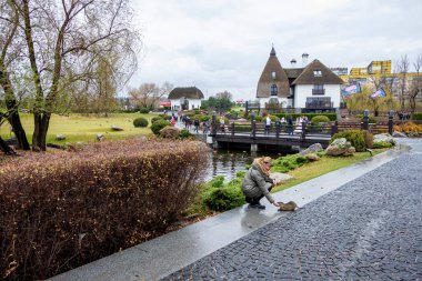 Paltolu kadın, besin, su sıçanı besliyor, özel yiyecekler yiyor, kemirgenler, nehir, yol, süs bitkileri, orijinal evler, ahşap köprüdeki insanlar, bulutlu, sonbahar, hayvan, ilginç, serin, eğlence parkı, seyahat, mimari, turizm, Avrupa, manzara
