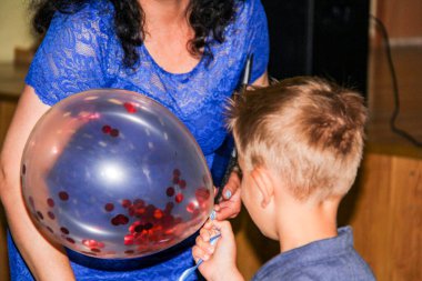 6 yaşında bir çocuk, içine şişme balon alıyor, içinde kırmızı pullar, takım elbise, kadın mavi elbise veriyor, tatil, tatil, çocuk, çocukluk, seyahat, arka plan, içeride tutma, eğitim, insanlar, okul, aile, kadın