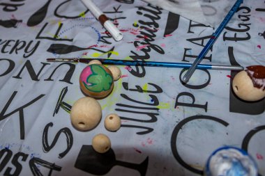 Yarı boyanmış boncuklar, masada uzanan, renkli boyalar, tahta kurusıkı, kolyeler, bilezikler, farklı bedenler, çok renkli, dekorasyon, çocuklar tarafından yapılmış, yaratıcılık, sanat, yakın çekim, el yapımı, fırça, ışıltı, lekeli masa 