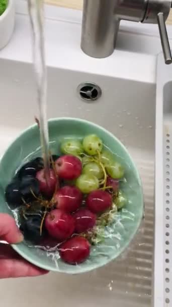 用自来水洗碗的手 用绿色 粉色和蓝色的葡萄束 — 图库视频影像