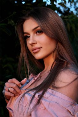 Genç ve güzel bir kadın gün batımında bir tarlada selfie çekiyor.