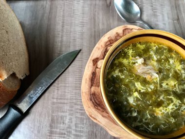 Bir kase yeşil kuş çorbası ve bir kaşık, kahvaltı için bir bıçak ve ekmek ya da öğle yemeği