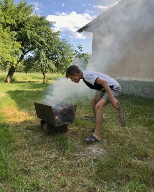 On iki yaşında bir çocuk barbekü ızgarasında ateş yakarken patlıyor.