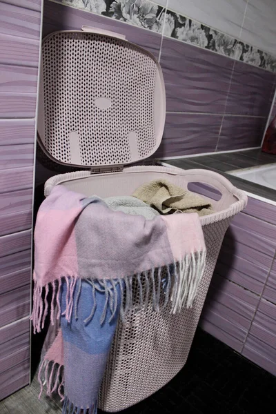 There is a pink basket with dirty laundry in the bathroom